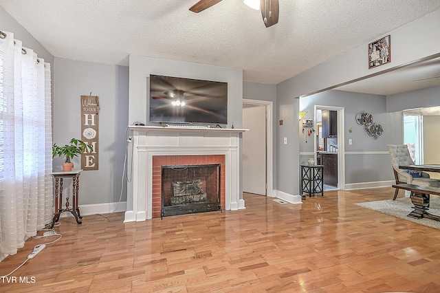 living room featuring a fireplace, light hardwood / wood-style floors, and a textured ceiling