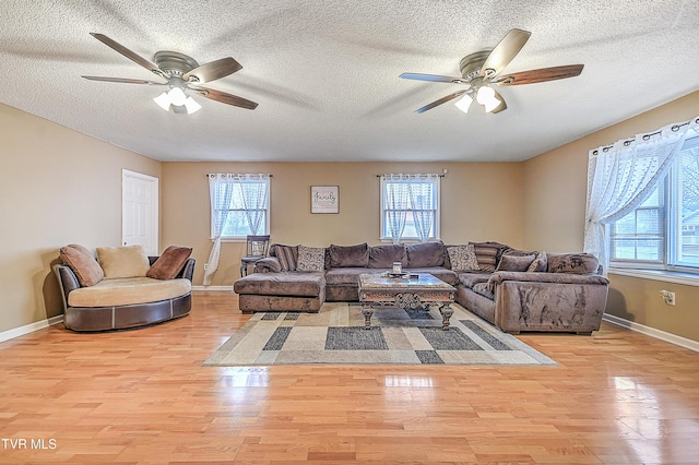 living room featuring ceiling fan, plenty of natural light, and light wood-type flooring