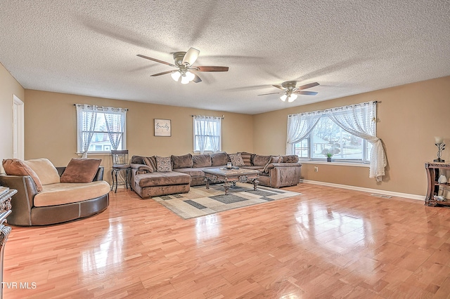 living room featuring ceiling fan, a healthy amount of sunlight, a textured ceiling, and light hardwood / wood-style floors