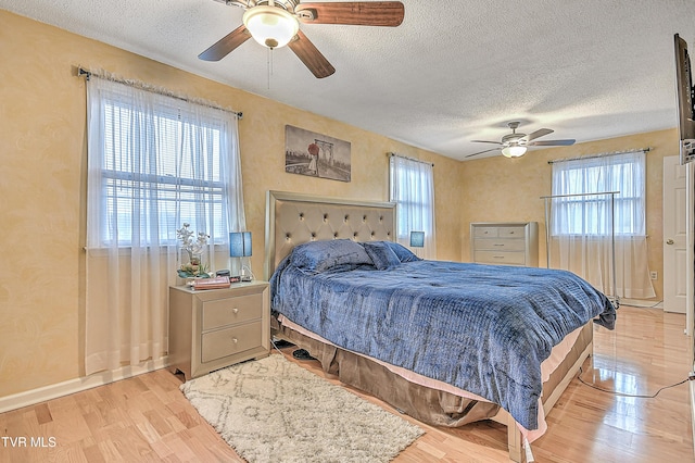 bedroom with multiple windows, light hardwood / wood-style flooring, and a textured ceiling