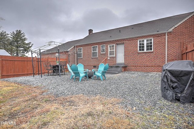 back of property with a gazebo, a patio area, and an outdoor fire pit