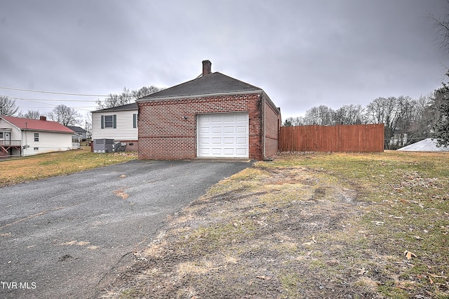 view of side of home with a garage, a yard, and central air condition unit