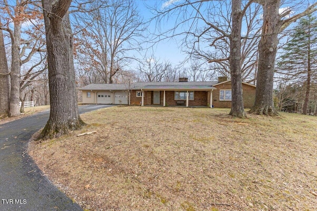 ranch-style house with brick siding, a chimney, an attached garage, driveway, and a front lawn