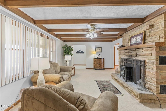 living area with baseboards, light colored carpet, ceiling fan, beamed ceiling, and a fireplace