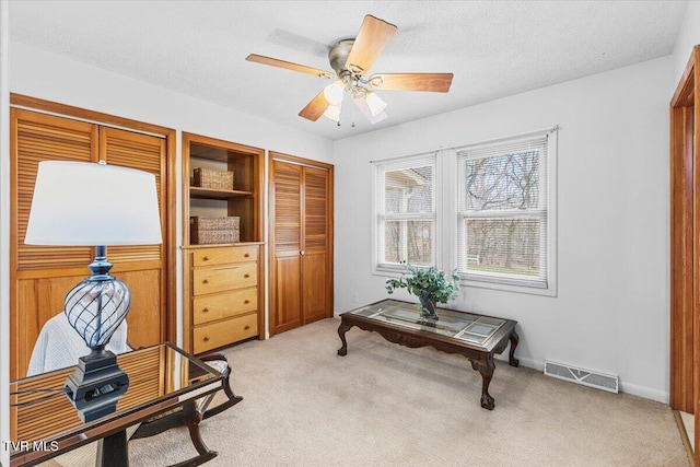 home office featuring light colored carpet, visible vents, a textured ceiling, and baseboards