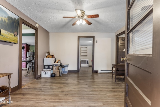 interior space featuring a baseboard heating unit, hardwood / wood-style floors, a textured ceiling, and ceiling fan