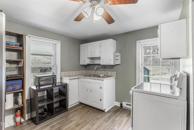 kitchen featuring a baseboard heating unit, plenty of natural light, sink, and white cabinets