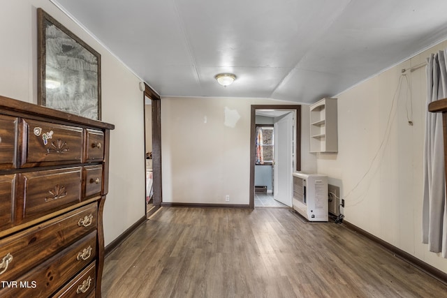 unfurnished living room featuring dark hardwood / wood-style floors, vaulted ceiling, and heating unit