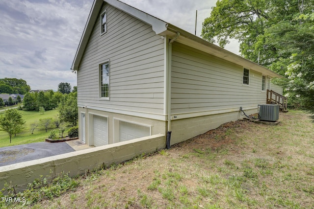 view of property exterior with central AC, driveway, and a garage