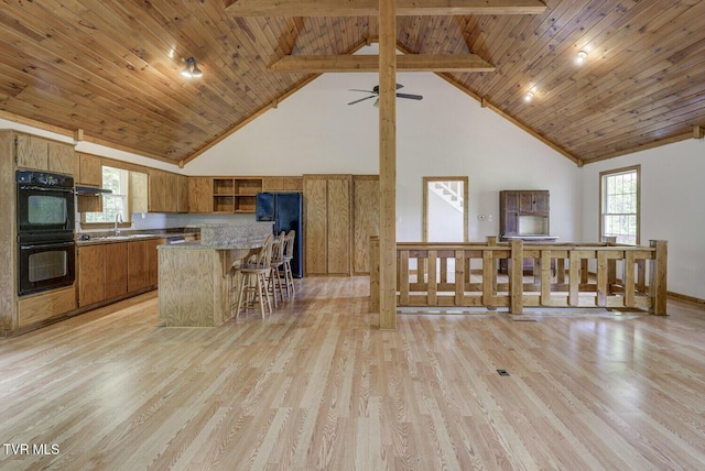 kitchen with brown cabinets, high vaulted ceiling, light wood finished floors, and black appliances