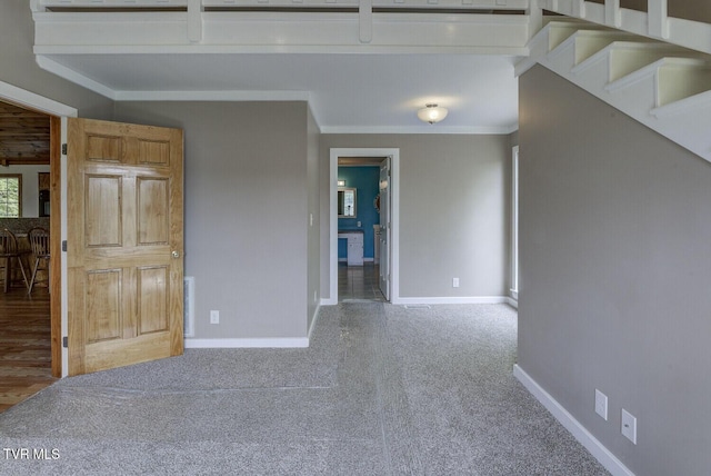 carpeted empty room with baseboards, ornamental molding, and stairway