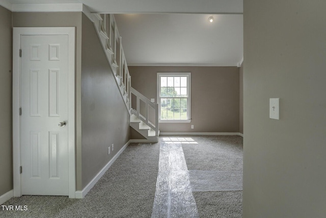 interior space featuring carpet flooring, baseboards, crown molding, and stairs