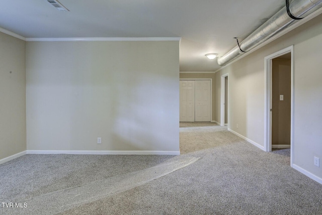 spare room with carpet floors, baseboards, crown molding, and visible vents