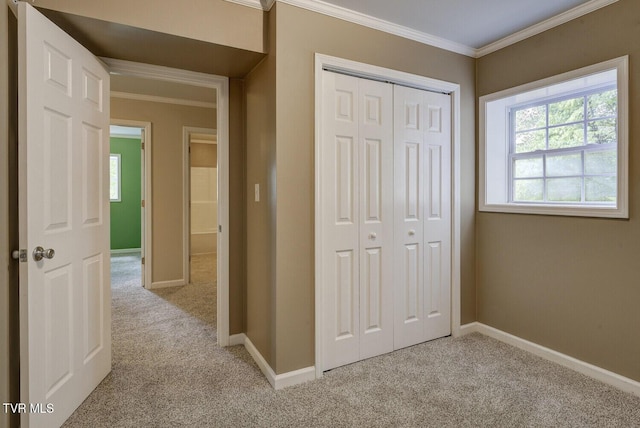 unfurnished bedroom featuring a closet, baseboards, crown molding, and light carpet