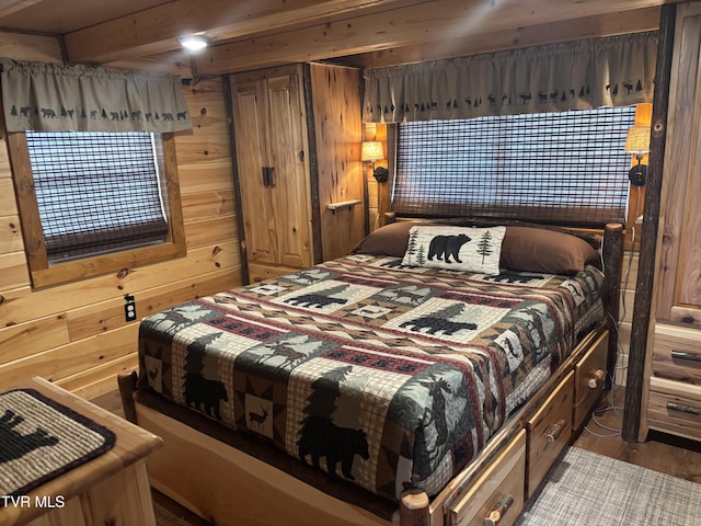 bedroom featuring beamed ceiling, hardwood / wood-style flooring, and wooden walls