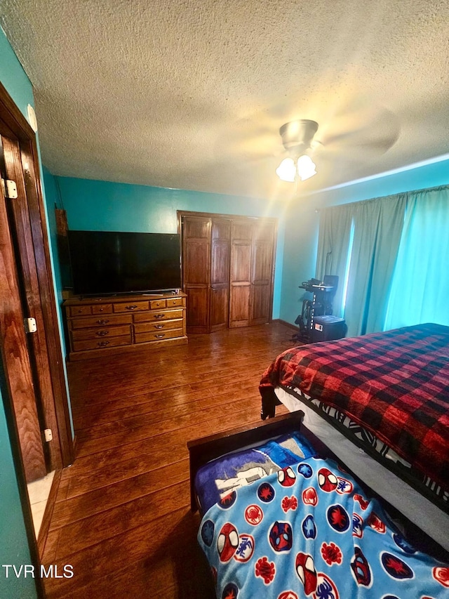 bedroom with ceiling fan, hardwood / wood-style flooring, and a textured ceiling