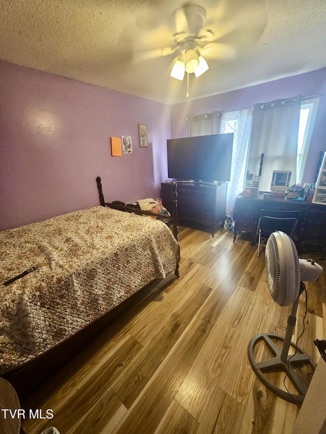 bedroom featuring ceiling fan, light hardwood / wood-style flooring, and a textured ceiling
