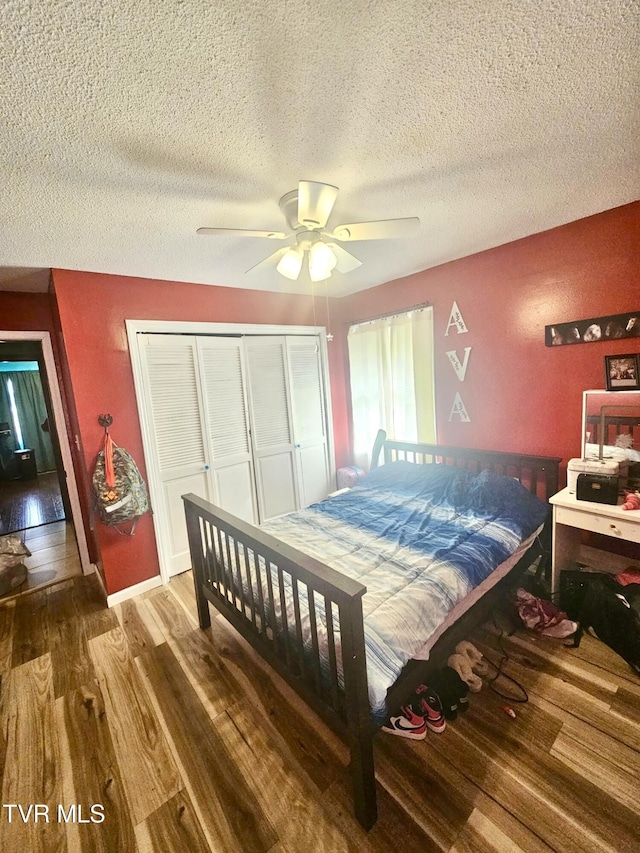 bedroom with hardwood / wood-style floors, a textured ceiling, a closet, and ceiling fan