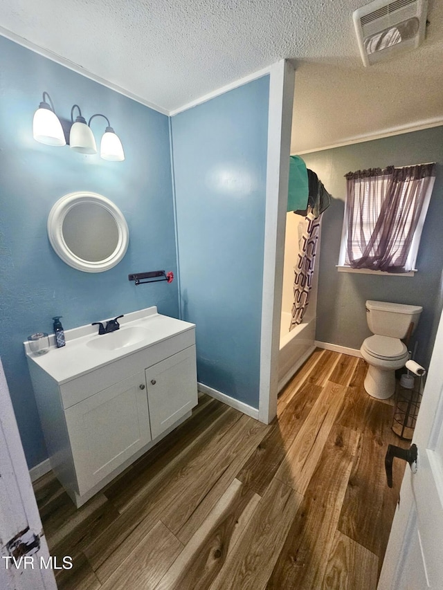 full bathroom with shower / bath combo, vanity, wood-type flooring, a textured ceiling, and toilet