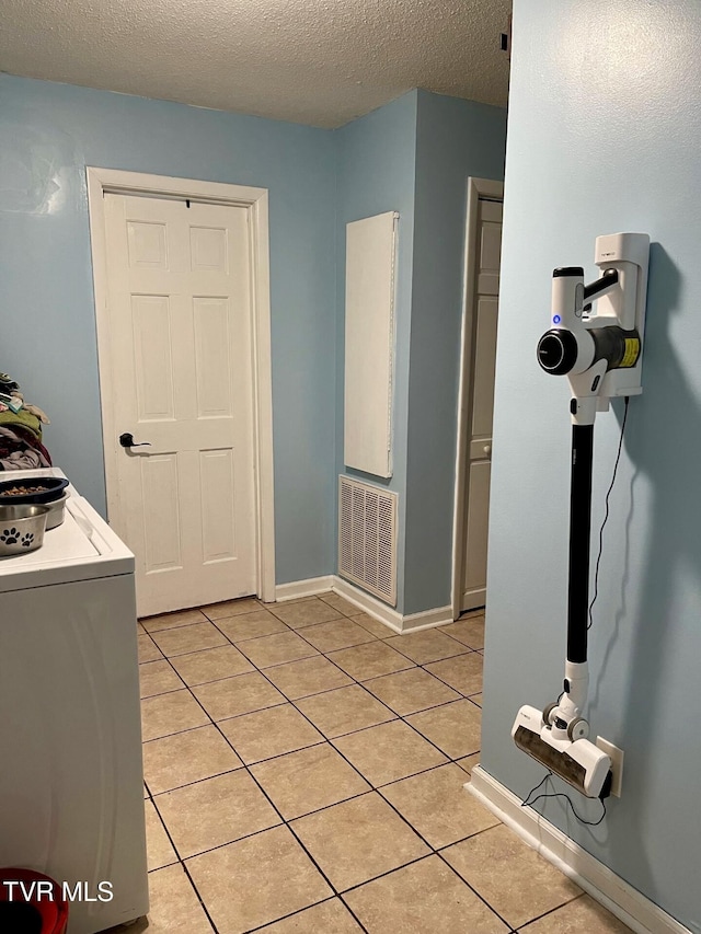 washroom featuring washer / clothes dryer, light tile patterned floors, and a textured ceiling