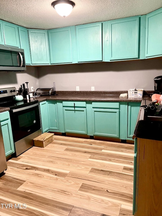 kitchen featuring green cabinetry, stainless steel appliances, light hardwood / wood-style flooring, and a textured ceiling