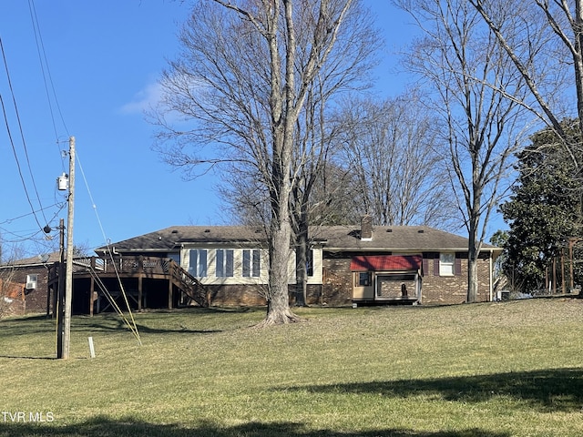 rear view of property featuring a deck and a lawn