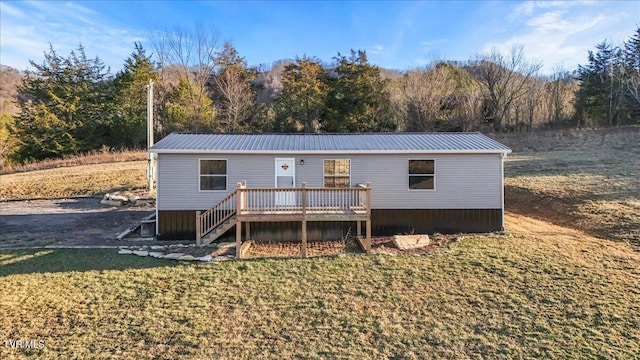 rear view of house featuring a wooden deck and a yard