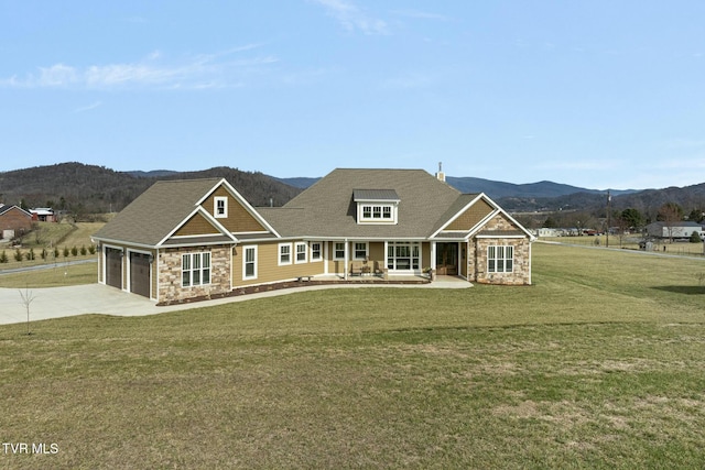 view of front of home featuring a garage, a mountain view, covered porch, and a front lawn