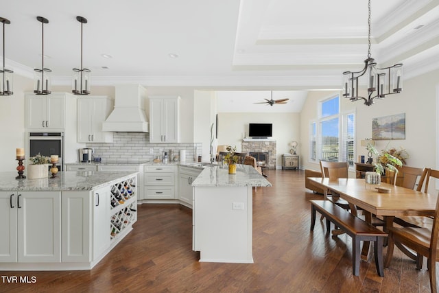 132 Hamilton Rd, Elizabethton, TN 37643 - kitchen featuring custom exhaust hood, white cabinetry, stainless steel oven, decorative light fixtures, and light stone countertops