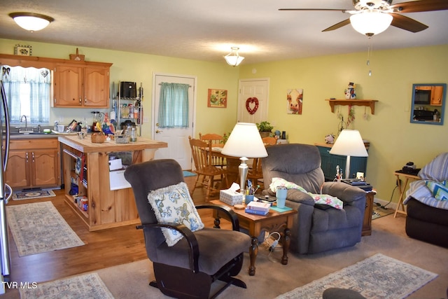 living room with sink, ceiling fan, and light wood-type flooring