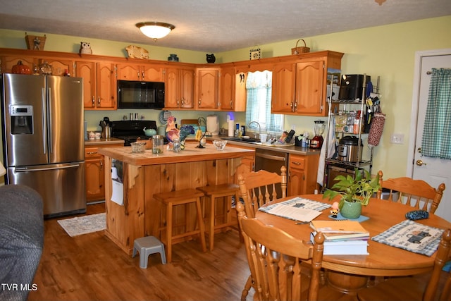 kitchen featuring dark hardwood / wood-style flooring, sink, a textured ceiling, and black appliances