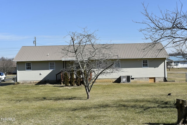 rear view of house with central AC unit and a lawn