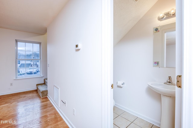 bathroom featuring wood-type flooring and a textured ceiling