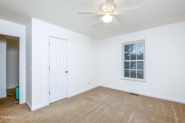 carpeted empty room featuring ceiling fan and a textured ceiling