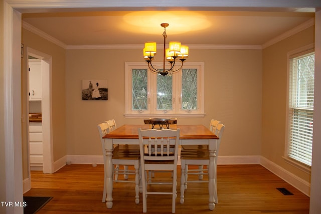 dining space featuring hardwood / wood-style flooring, crown molding, and a notable chandelier