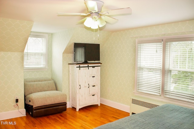 bedroom featuring radiator, hardwood / wood-style floors, and ceiling fan