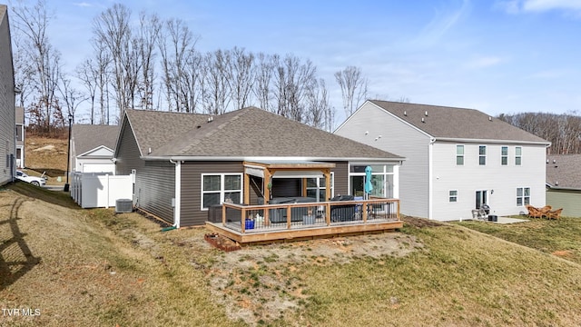 back of house with cooling unit, a deck, and a lawn