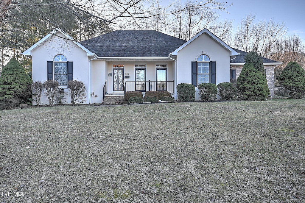 ranch-style house featuring covered porch and a front lawn