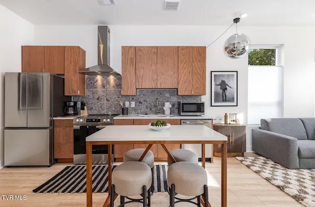 kitchen with tasteful backsplash, sink, hanging light fixtures, stainless steel appliances, and wall chimney exhaust hood