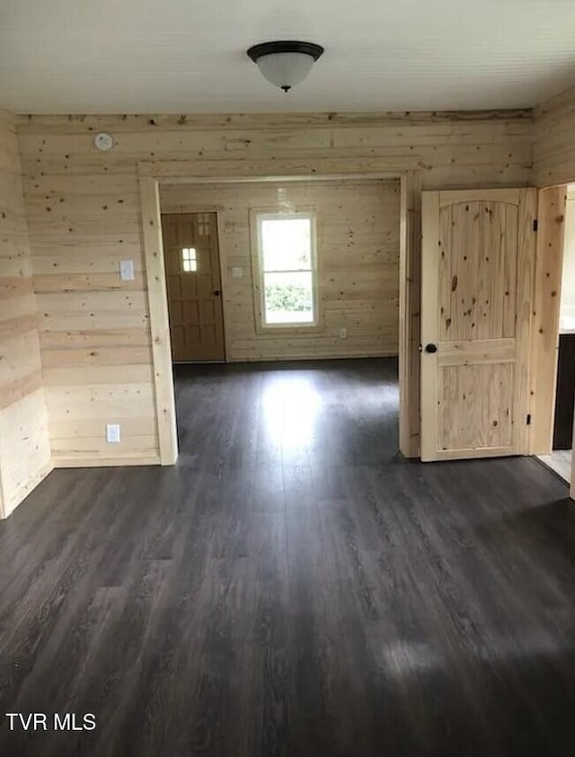 unfurnished room with dark hardwood / wood-style flooring and wooden walls