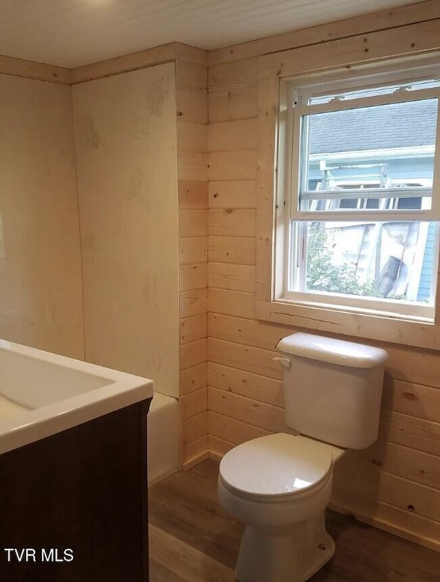 bathroom with hardwood / wood-style flooring, vanity, wooden walls, and toilet