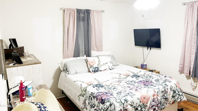 bedroom with a baseboard heating unit and dark wood-type flooring