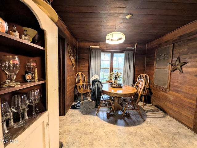 dining room featuring wooden ceiling and wood walls