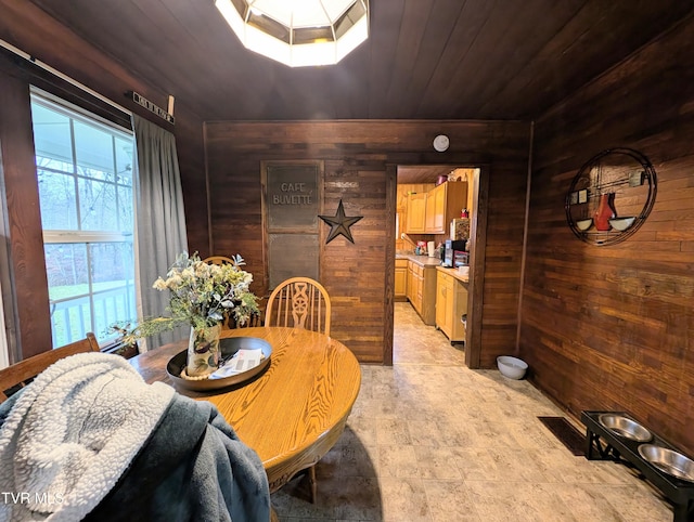 dining space with wood ceiling, a skylight, and wood walls