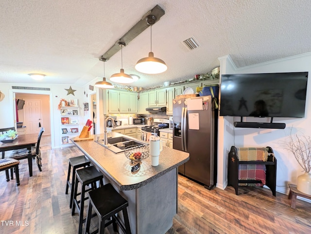 kitchen featuring sink, green cabinets, stainless steel appliances, dark hardwood / wood-style floors, and a kitchen bar