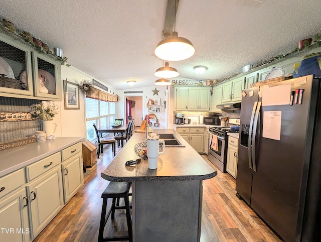 kitchen with lofted ceiling, sink, a kitchen bar, a kitchen island with sink, and stainless steel appliances