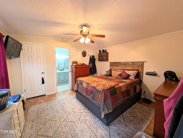 bedroom with ensuite bath, ceiling fan, a textured ceiling, vaulted ceiling, and light wood-type flooring