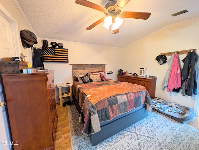 bedroom with ornamental molding, lofted ceiling, a textured ceiling, and light hardwood / wood-style flooring