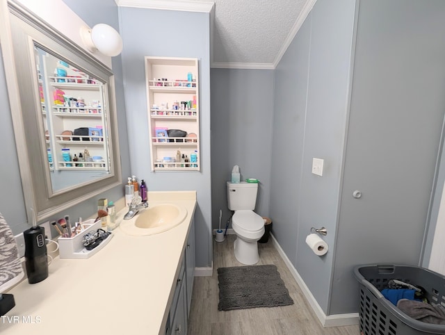 bathroom with hardwood / wood-style floors, vanity, toilet, crown molding, and a textured ceiling