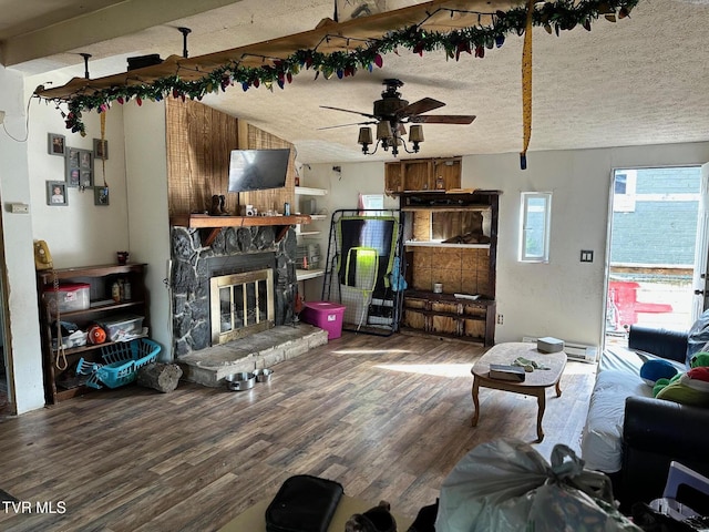 living room featuring hardwood / wood-style flooring, ceiling fan, a textured ceiling, and a fireplace